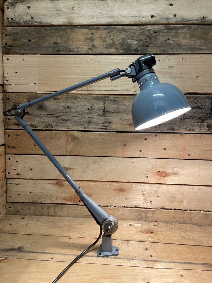 an industrial style desk lamp on top of a wooden floor next to a wood wall