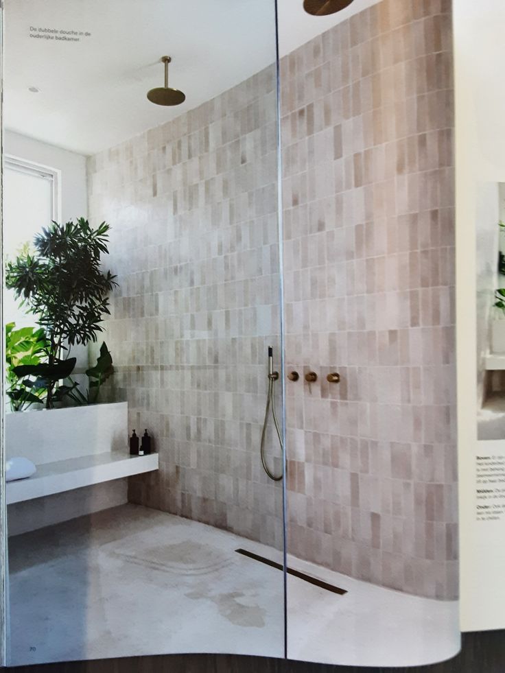 an open magazine showing a bathroom with tiled walls and floors, including a walk - in shower