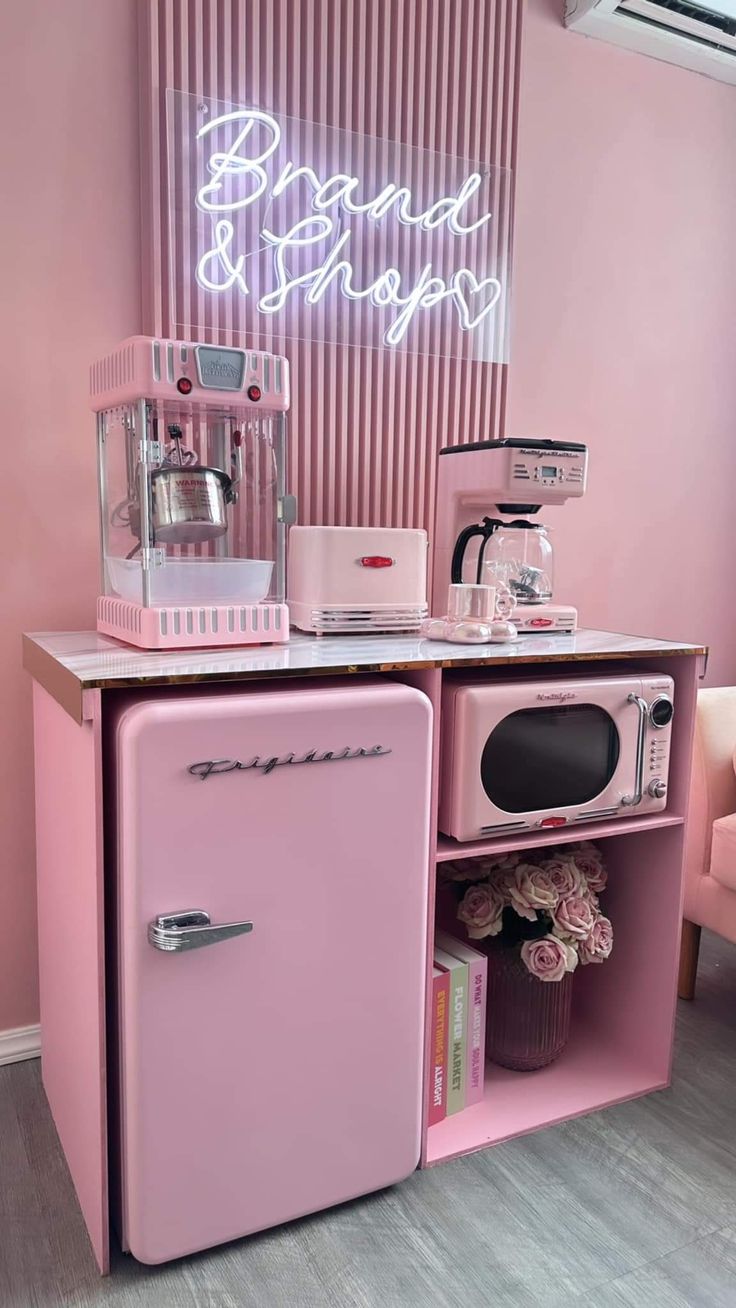 a pink kitchen with an old fashioned refrigerator and coffee maker on the counter in front of it