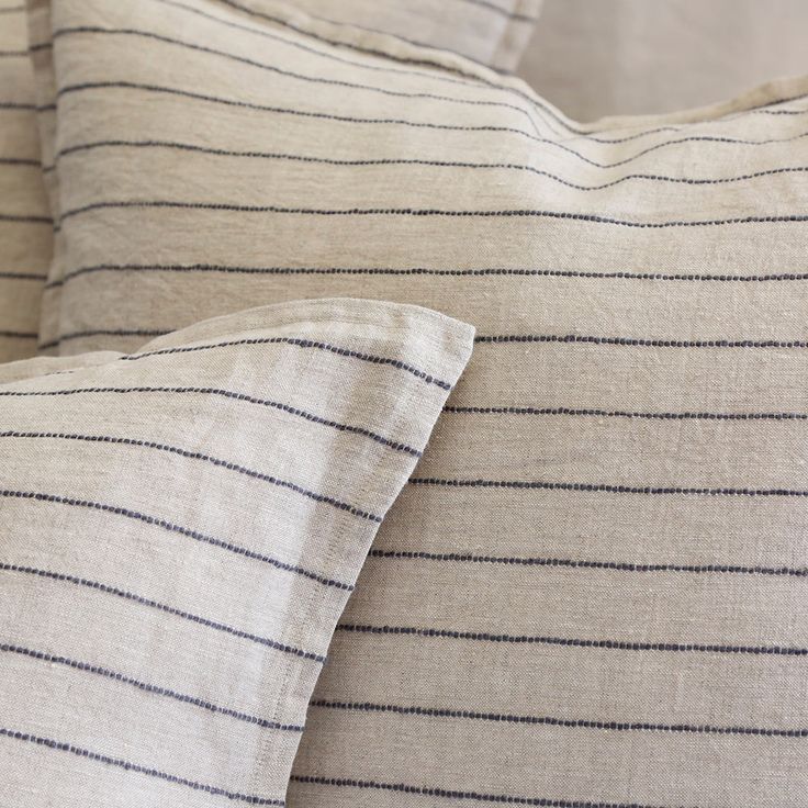 two pillows with black and white striped linens on them, one is folded over the other