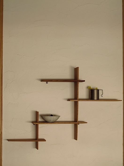 three wooden shelves with bowls and cups on them against a wall in a living room