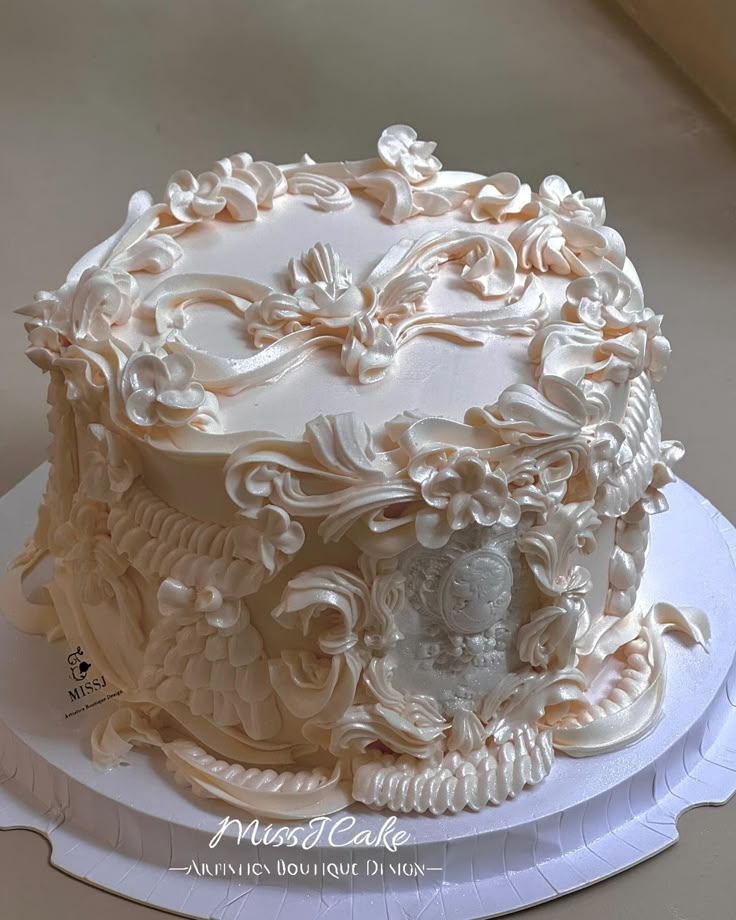 a large white cake on top of a plate with flowers and scrolls around it's edges