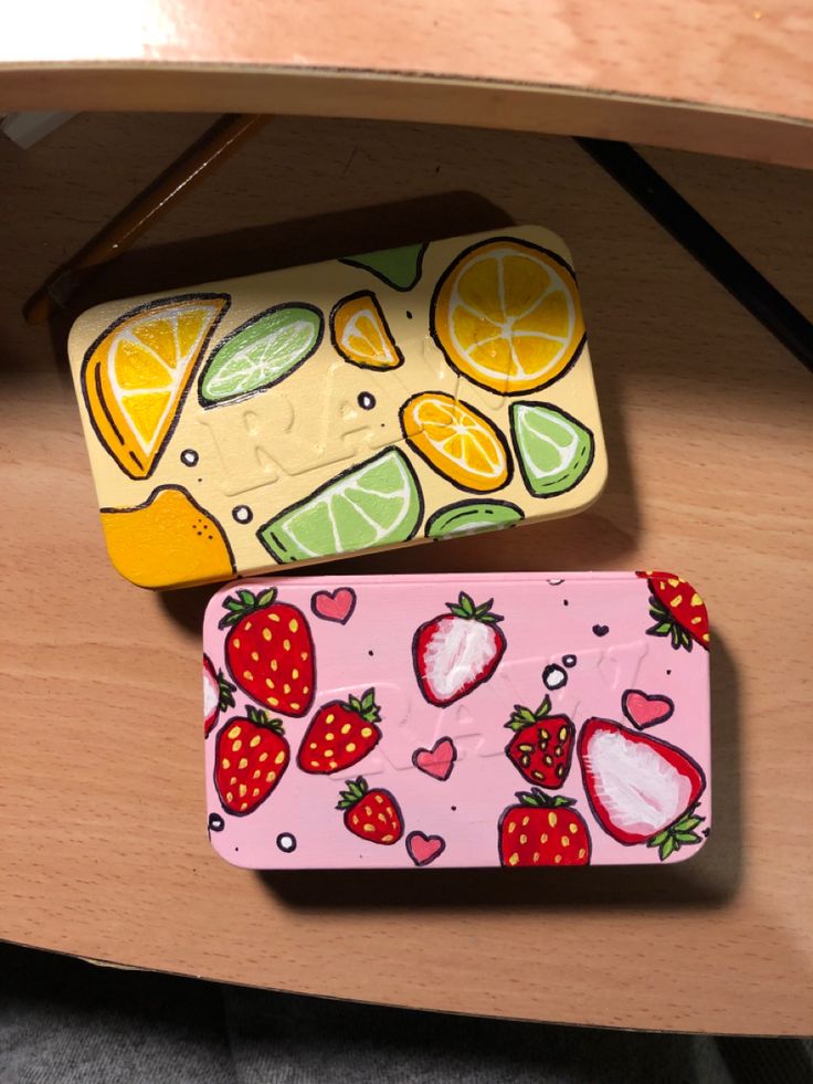 two cell phones sitting next to each other on a wooden table with oranges, lemons and strawberries