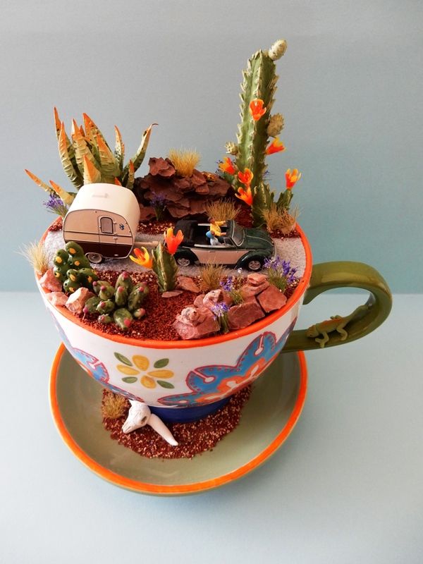 a cup filled with plants and rocks on top of a saucer