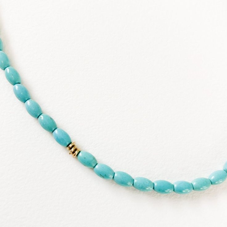 a blue beaded necklace with gold clasps on a white background, close up