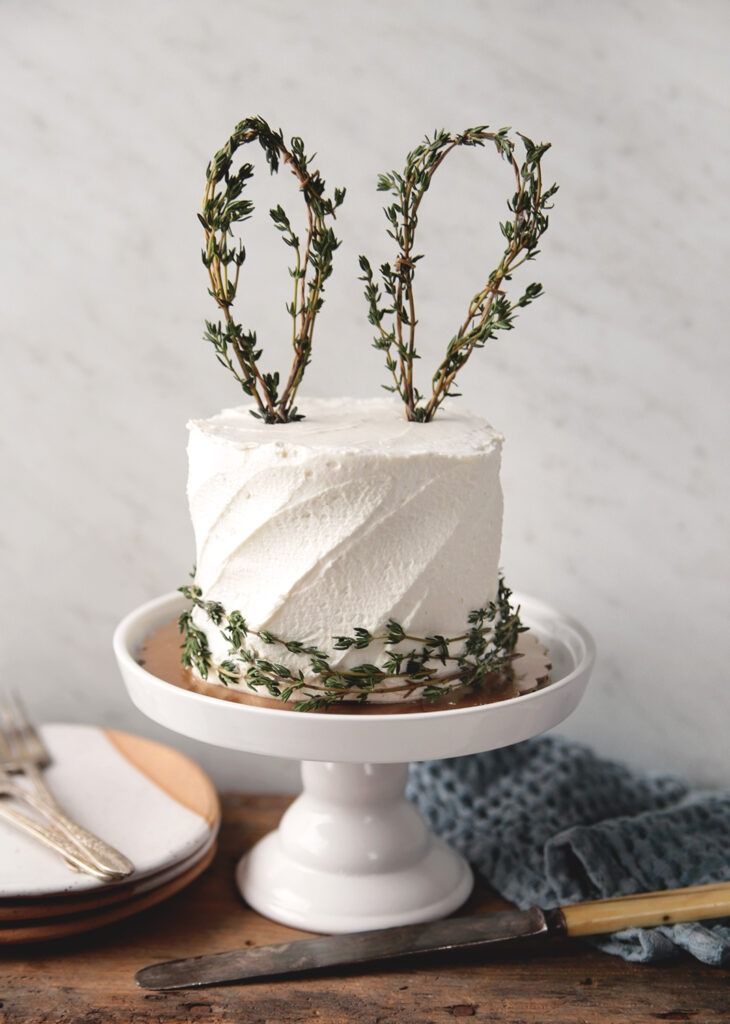 there is a cake with white frosting and greenery on the top that says love