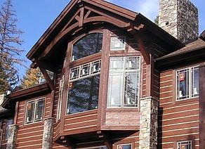 a large wooden house with windows and a clock tower