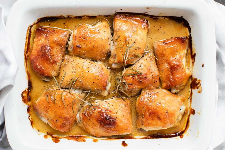 a casserole dish filled with chicken covered in gravy and garnished with rosemary