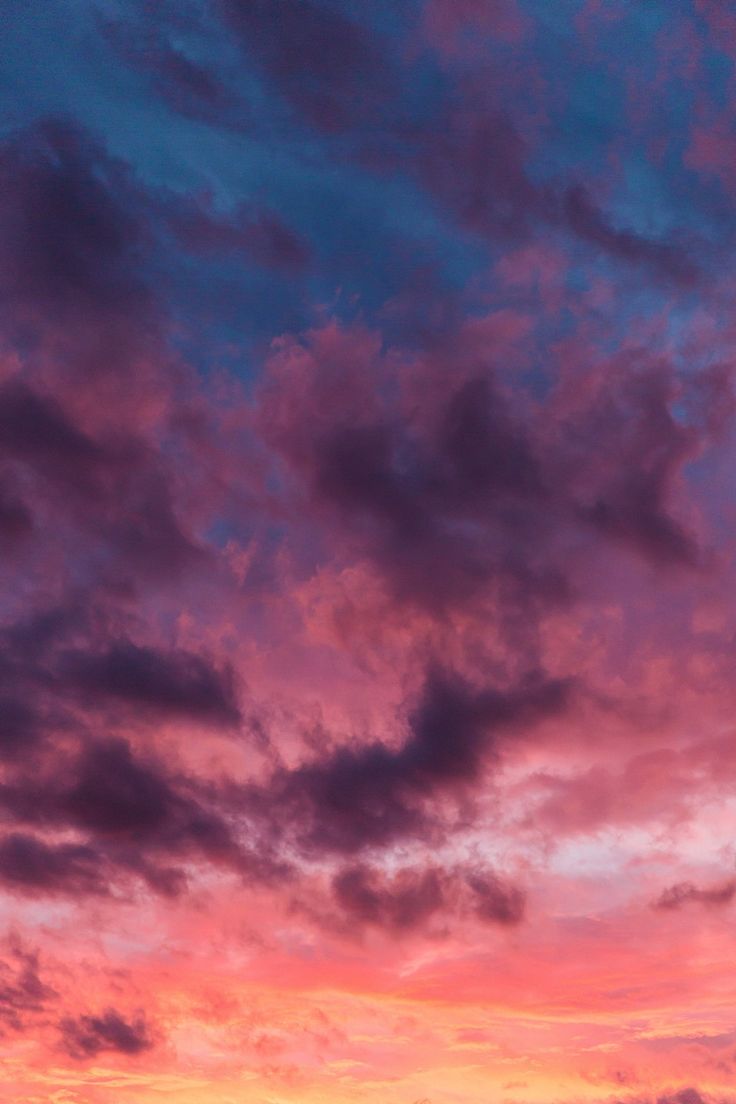 the sky is pink and blue as it sets in the distance with some clouds above