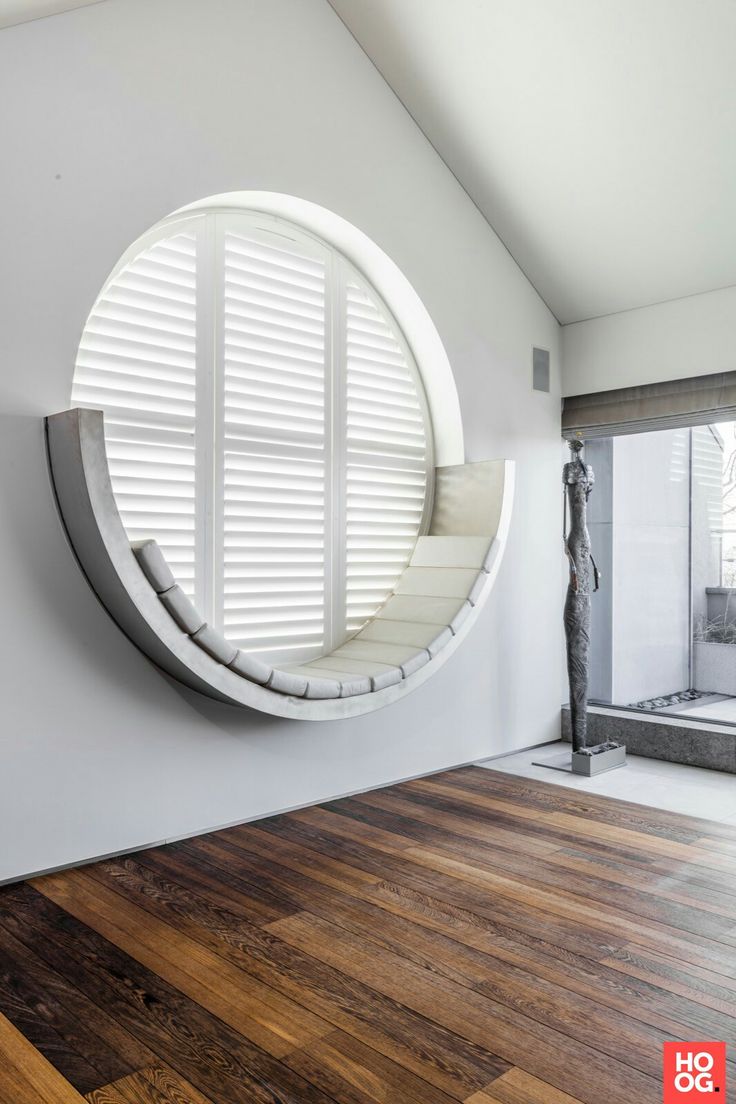 a circular mirror on the wall in a room with wood flooring and white walls