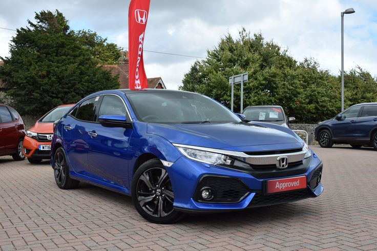 a blue honda civic is parked in front of some other cars on a brick road