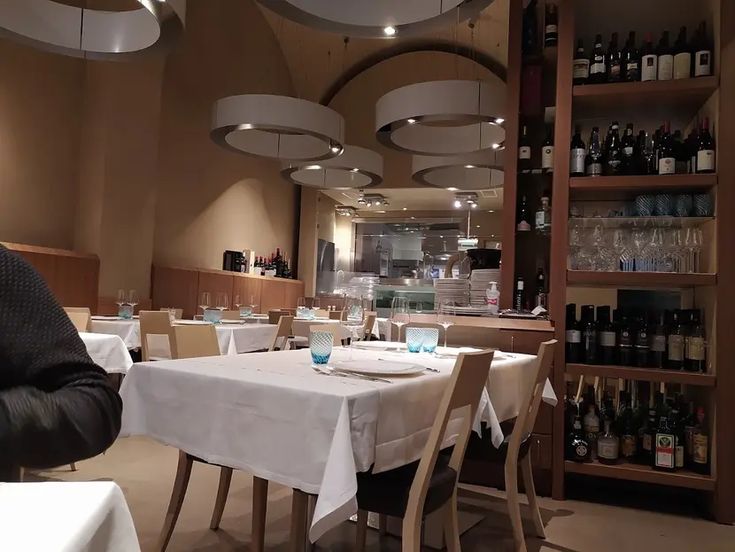 a man sitting at a table in a restaurant with wine bottles on the shelves behind him