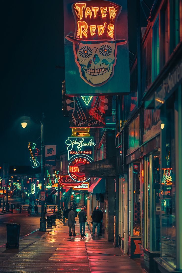 people are walking down the street in front of neon signs and buildings at night time