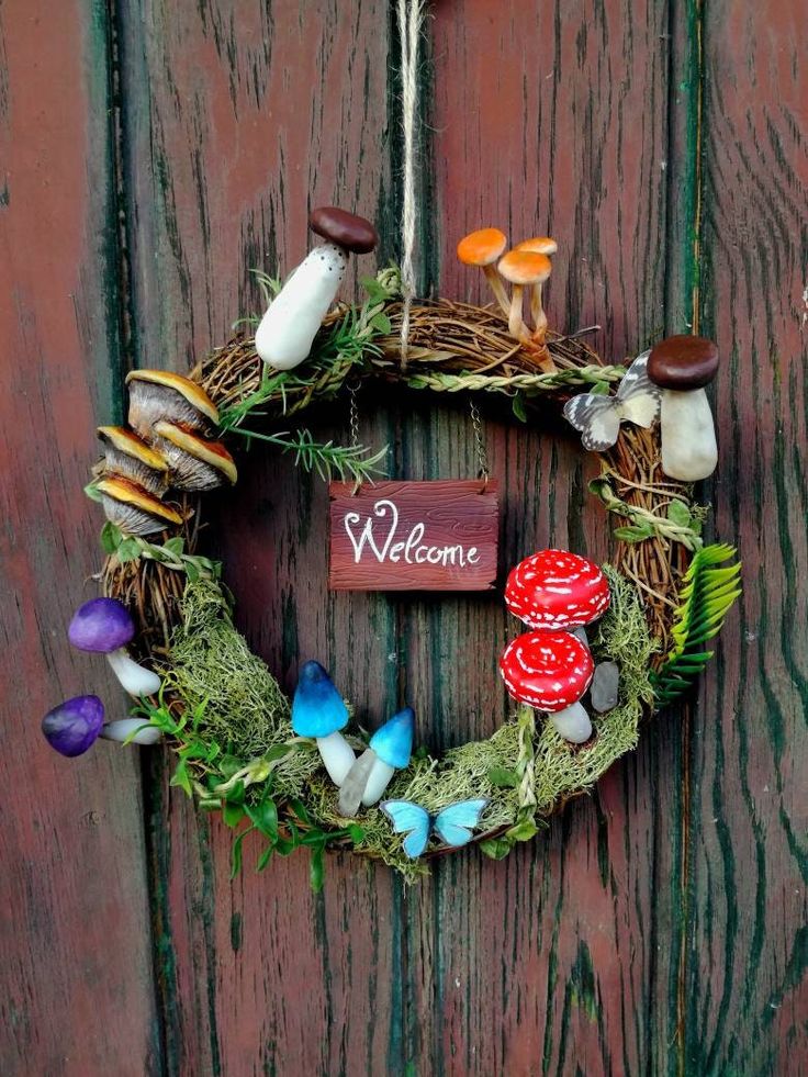 a welcome wreath with mushrooms and leaves hanging on a wooden door