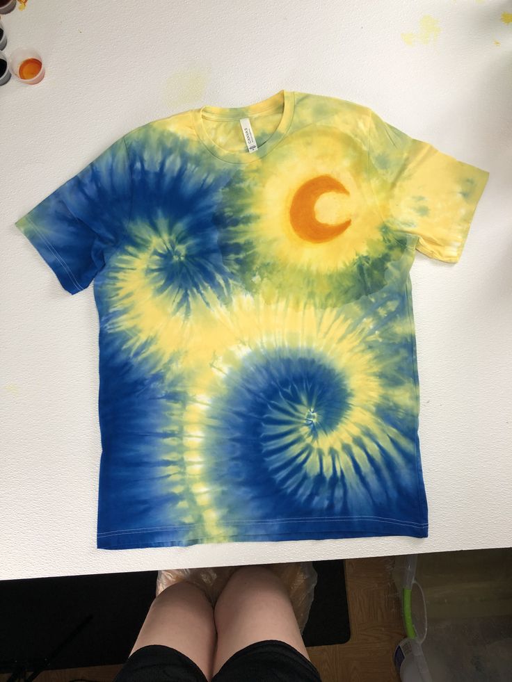 a person standing next to a tie - dyed shirt with the letter c on it