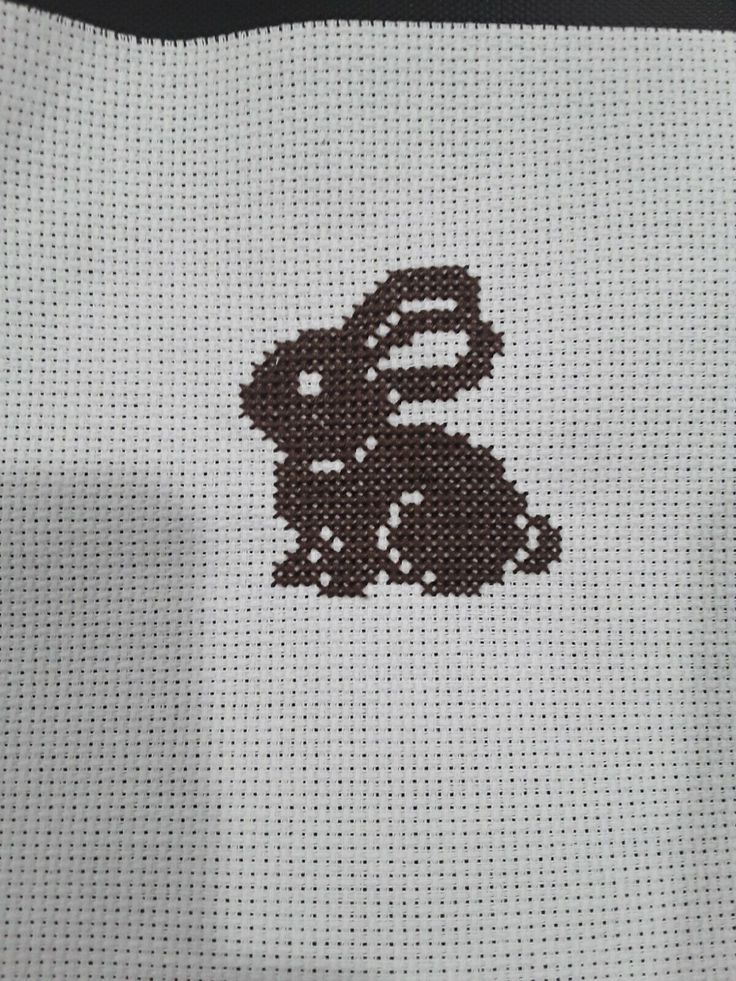 a cross - stitch bunny is shown on the back of a white bag with brown trim