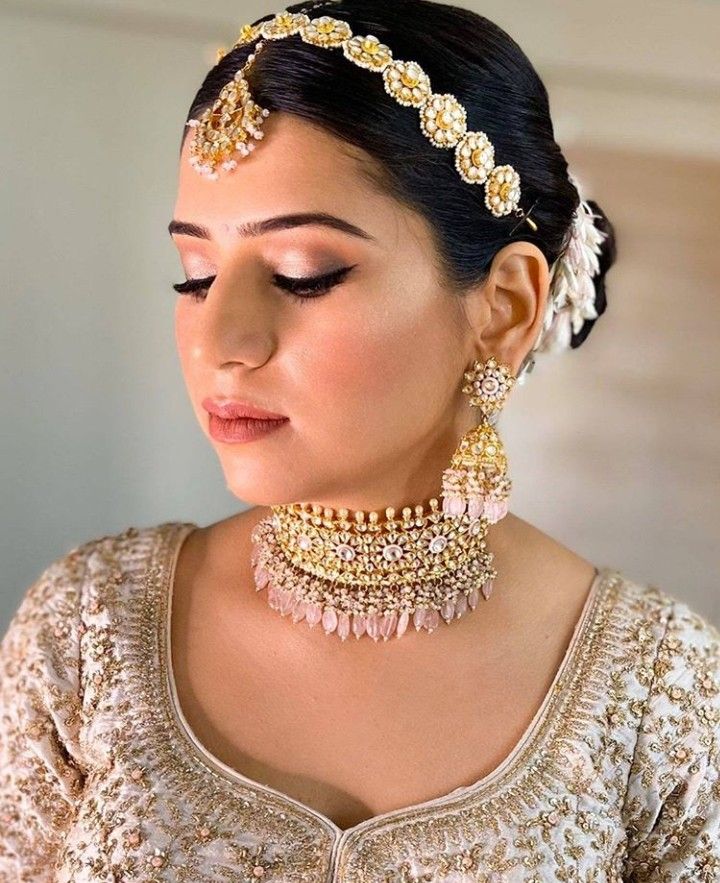 a woman wearing a gold and white outfit with jewelry on her head, looking down at the