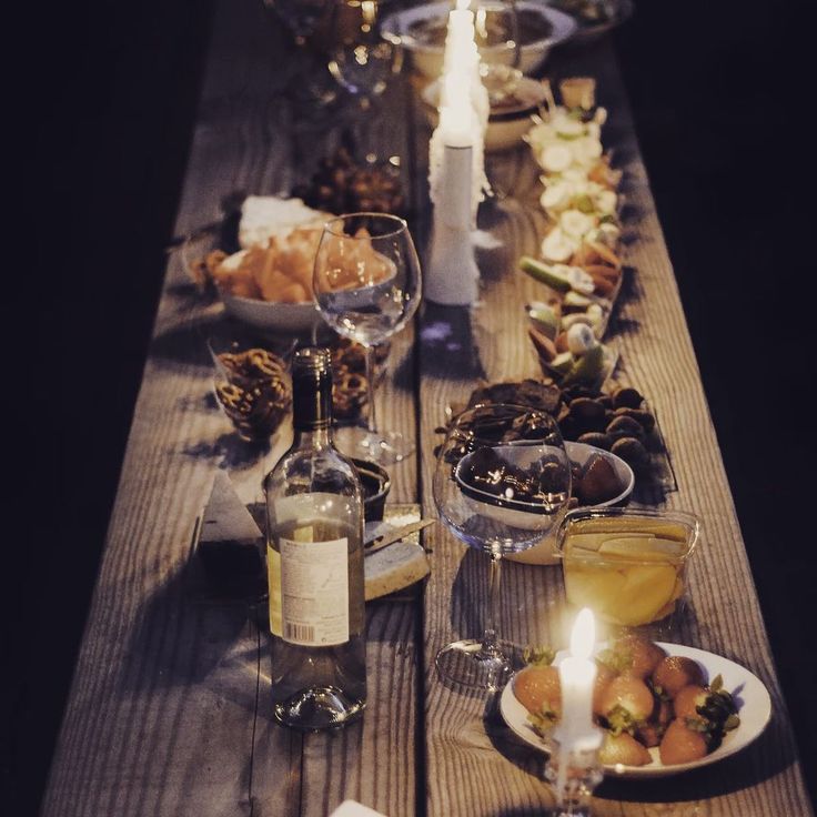 a long table is set with wine, food and candles for an elegant dinner party