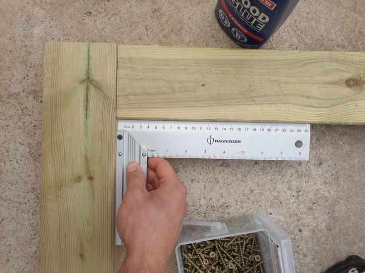 a person measuring wood with a ruler and screwdriver on the floor next to it