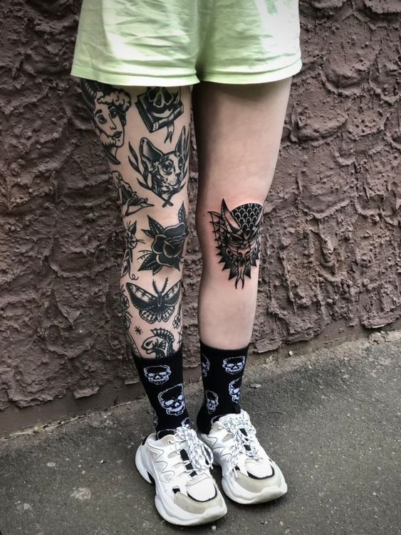 a person with tattoos on their legs standing next to a wall