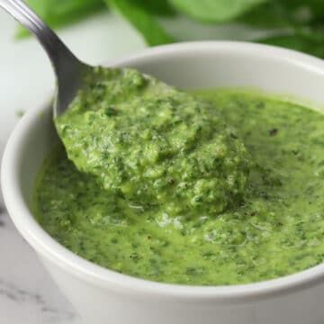 a white bowl filled with green sauce and a spoon