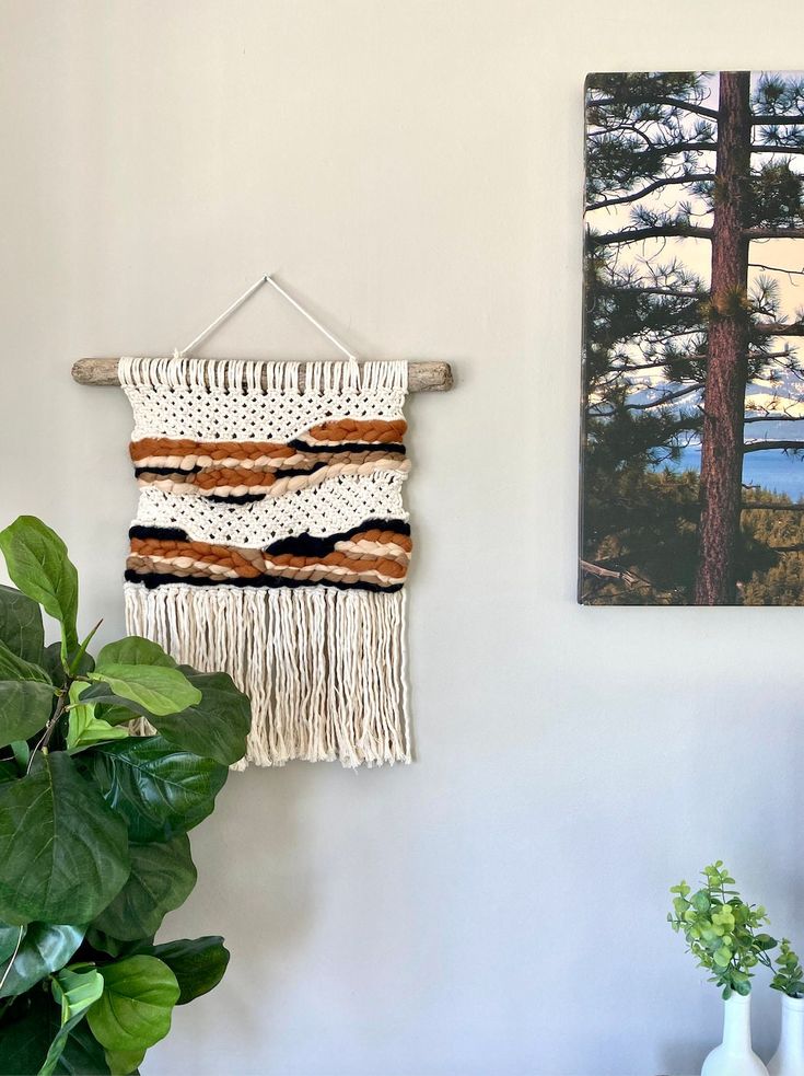 two paintings hang on the wall next to a potted plant and a wooden table