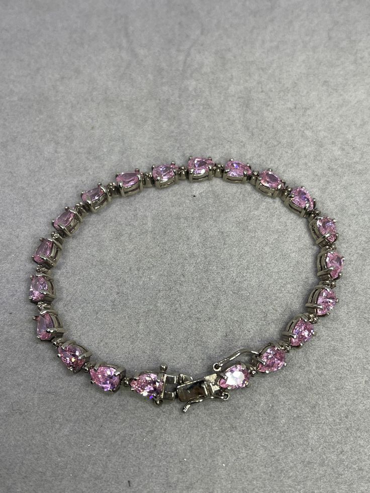 This is a beautiful pink CZ sterling silver bracelet. This bracelet features 20 pear cut pink CZs with each of them measuring 7x5 MM. The pink CZ show a strong fire and they're very transparent as they look like fine pink sapphires. The bracelet is approximately 8.5 inches in length. This bracelet is stamped 925 as well. This item is new and unworn. Silver Pear-shaped Bracelets For Anniversary, Silver Pear-shaped Anniversary Bracelets, Pear-shaped Silver Bracelet For Anniversary, Elegant Pink Sterling Silver Bracelets, Elegant Pink Sterling Silver Round Bracelet, Elegant Pink Sterling Silver Bracelet, Silver And Pink Jewelry, Formal Pink Gemstone Tennis Bracelet, Pink Heart Cut Sparkling Stones Jewelry