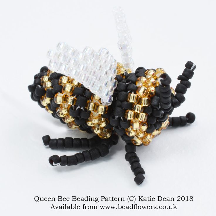 two beaded butterfly brooches sitting on top of each other in black and gold