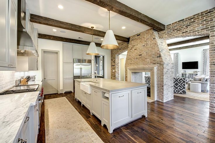 a large kitchen with an island in the middle and wood flooring on the other side