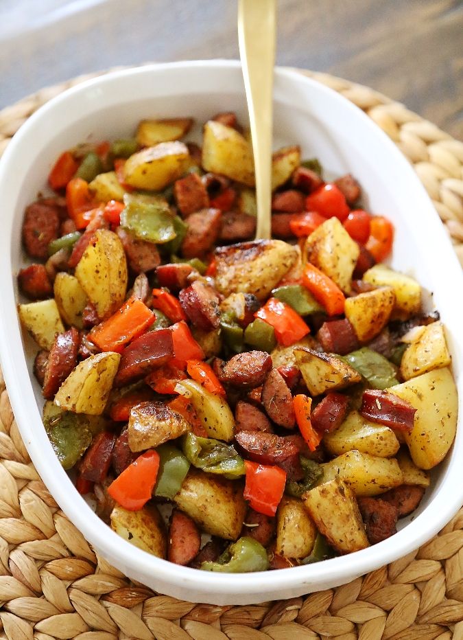 a white bowl filled with potatoes and carrots on top of a woven place mat