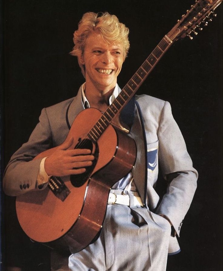 a man in a suit holding an acoustic guitar