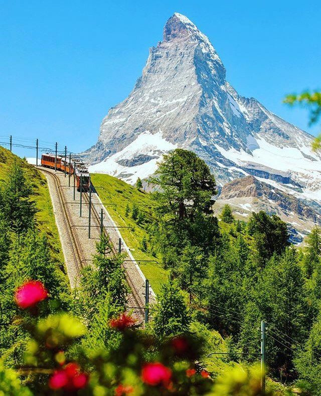 the train is going down the tracks in the mountains