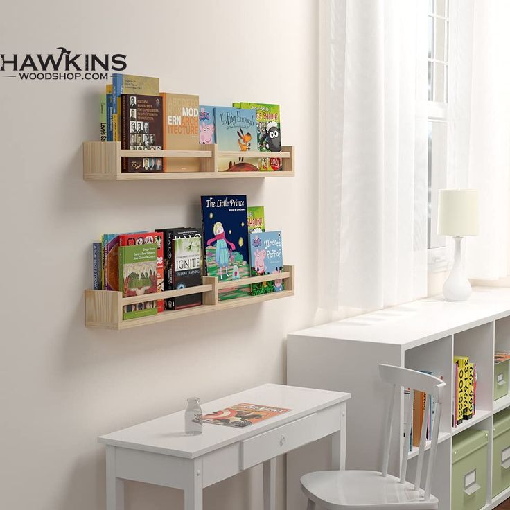 two wooden shelves with books on them next to a white table and chair in front of a window