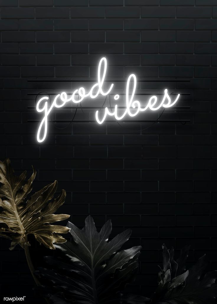 a neon sign that says good vibes in front of a brick wall with plants