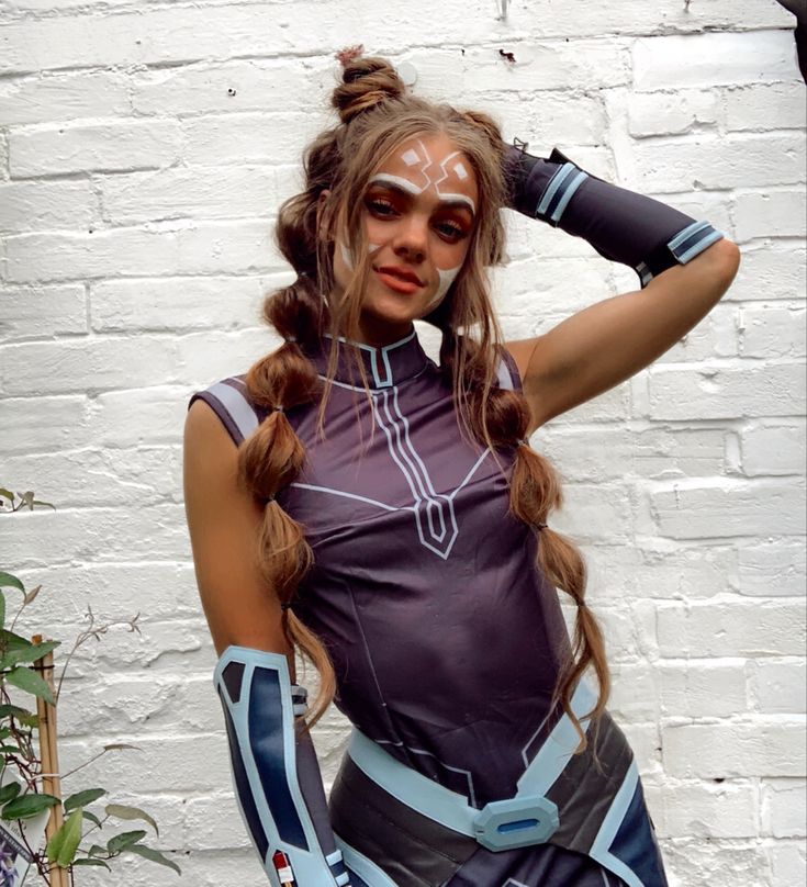 a woman with makeup on her face and arm is standing in front of a white brick wall