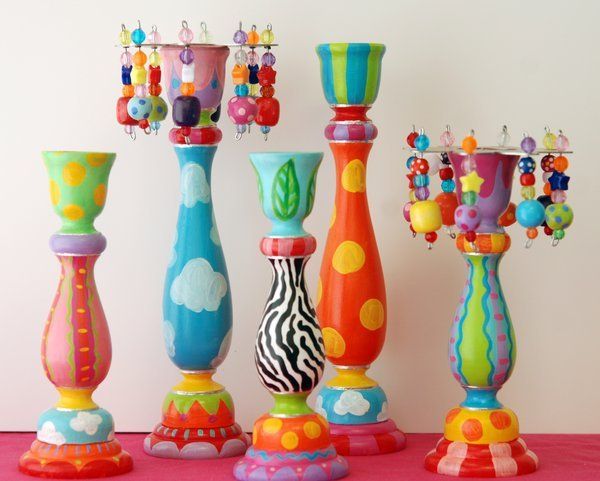 several colorful vases are lined up on a pink tablecloth with beads hanging from them