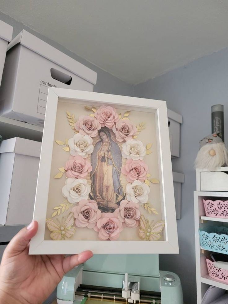 a person holding up a framed photo in front of some crafting supplies and sewing machines