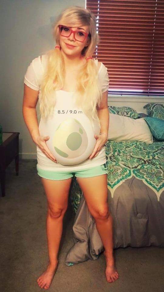 a pregnant woman is standing in front of a bed with her hands on her hips