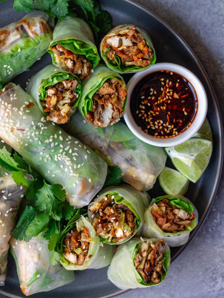 a plate filled with rolls covered in meat and lettuce next to dipping sauce