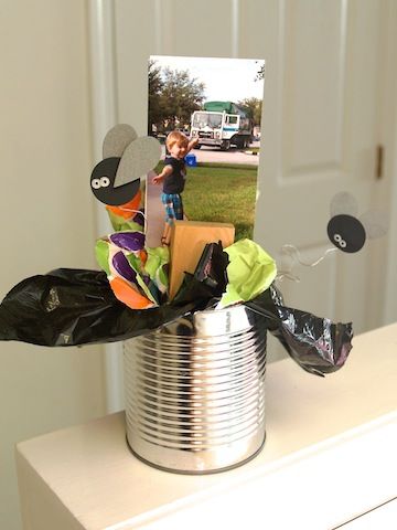 a tin can with some pictures in it on top of a white table next to a door