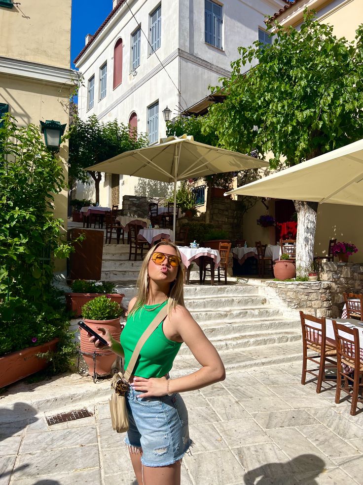 a woman standing in front of some tables and chairs with an umbrella over her head