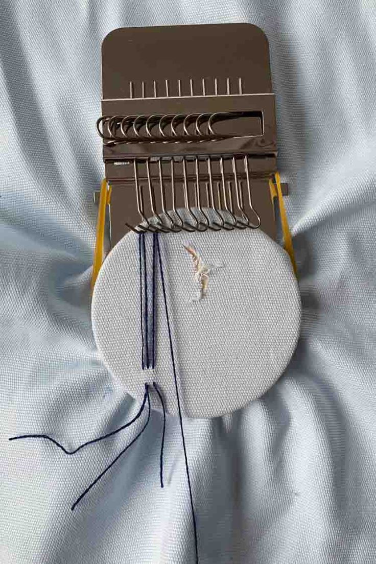 a close up of a sewing machine on a white sheet with blue and yellow thread