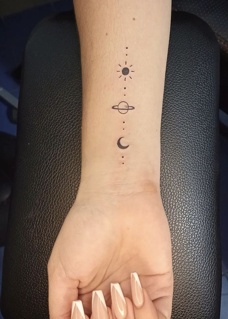 a woman's hand with a small tattoo on her wrist and the sun and moon