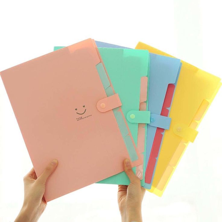 a person holding up five different colored folders with faces on the front and one in the back