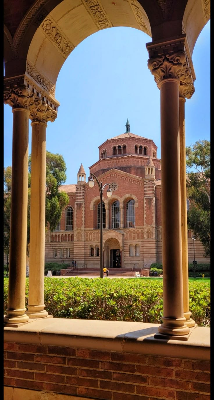 an old building with columns and arches in the foreground, surrounded by greenery