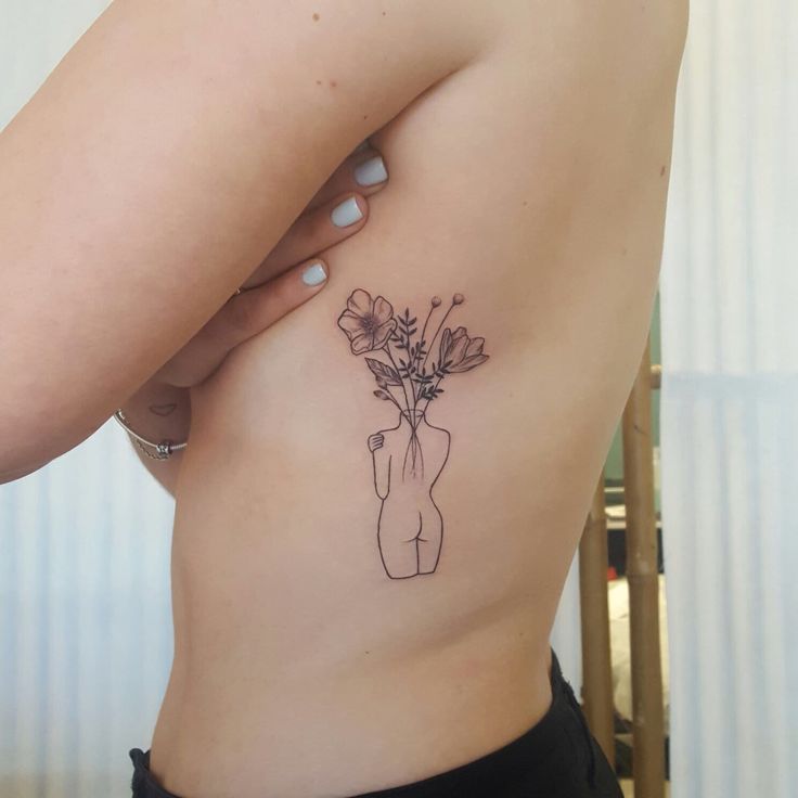 a woman's stomach with a flower tattoo on her left side ribcage