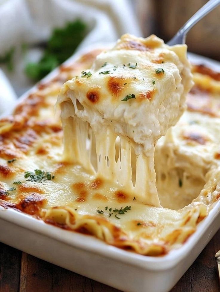 a piece of lasagna being lifted with a fork from a casserole dish