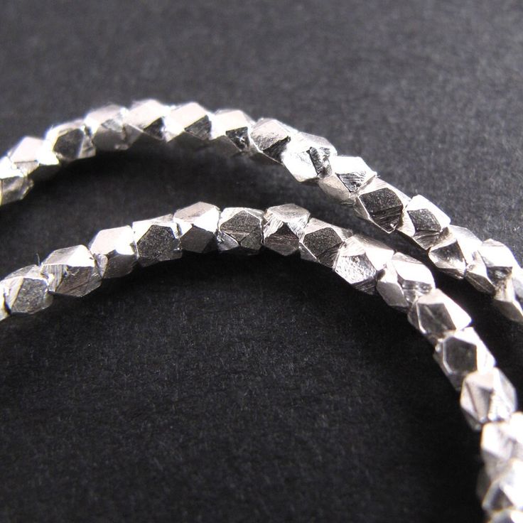 two silver bracelets on a black surface