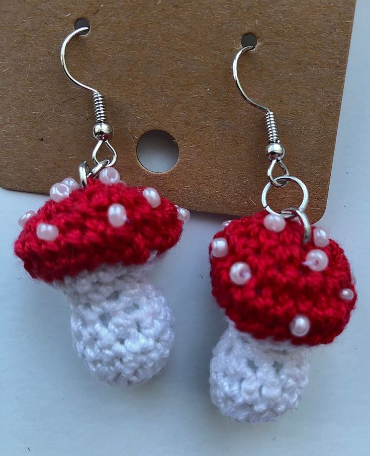 crocheted red and white mushroom earrings with pearls on the end, hanging from hooks