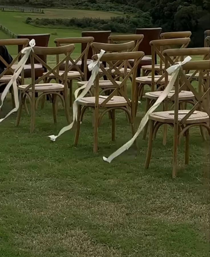 rows of wooden chairs with white ribbons tied to them